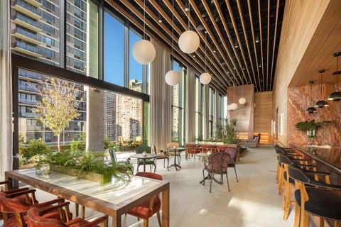 Modern high-rise interior with dining area, floor-to-ceiling windows overlooking cityscape, wooden ceiling details, and contemporary furnishings